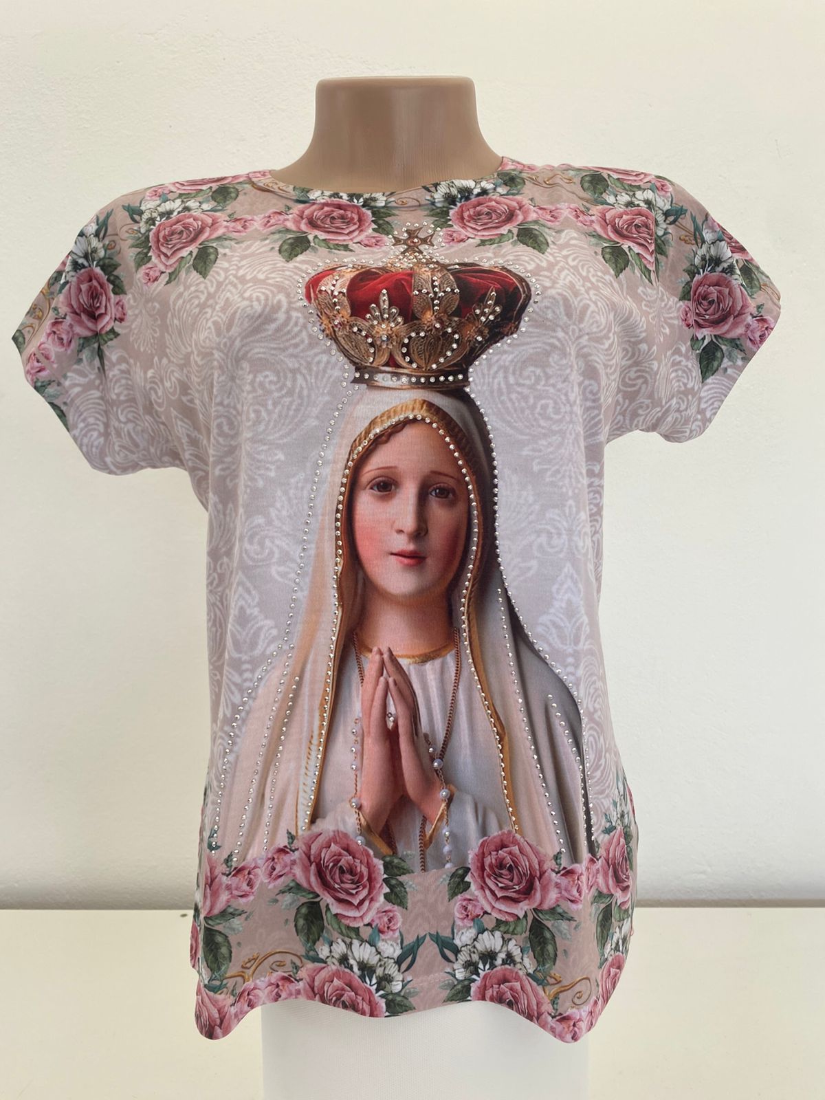 A camisa de Nossa Senhora de Fátima é uma peça de vestuário que geralmente apresenta imagens ou símbolos relacionados à aparição da Virgem Maria em Fátima, Portugal, em 1917. Essas camisas podem ser usadas por devotos como uma forma de expressar sua fé e devoção. Nossas camisas são em algodão e de qualidade.